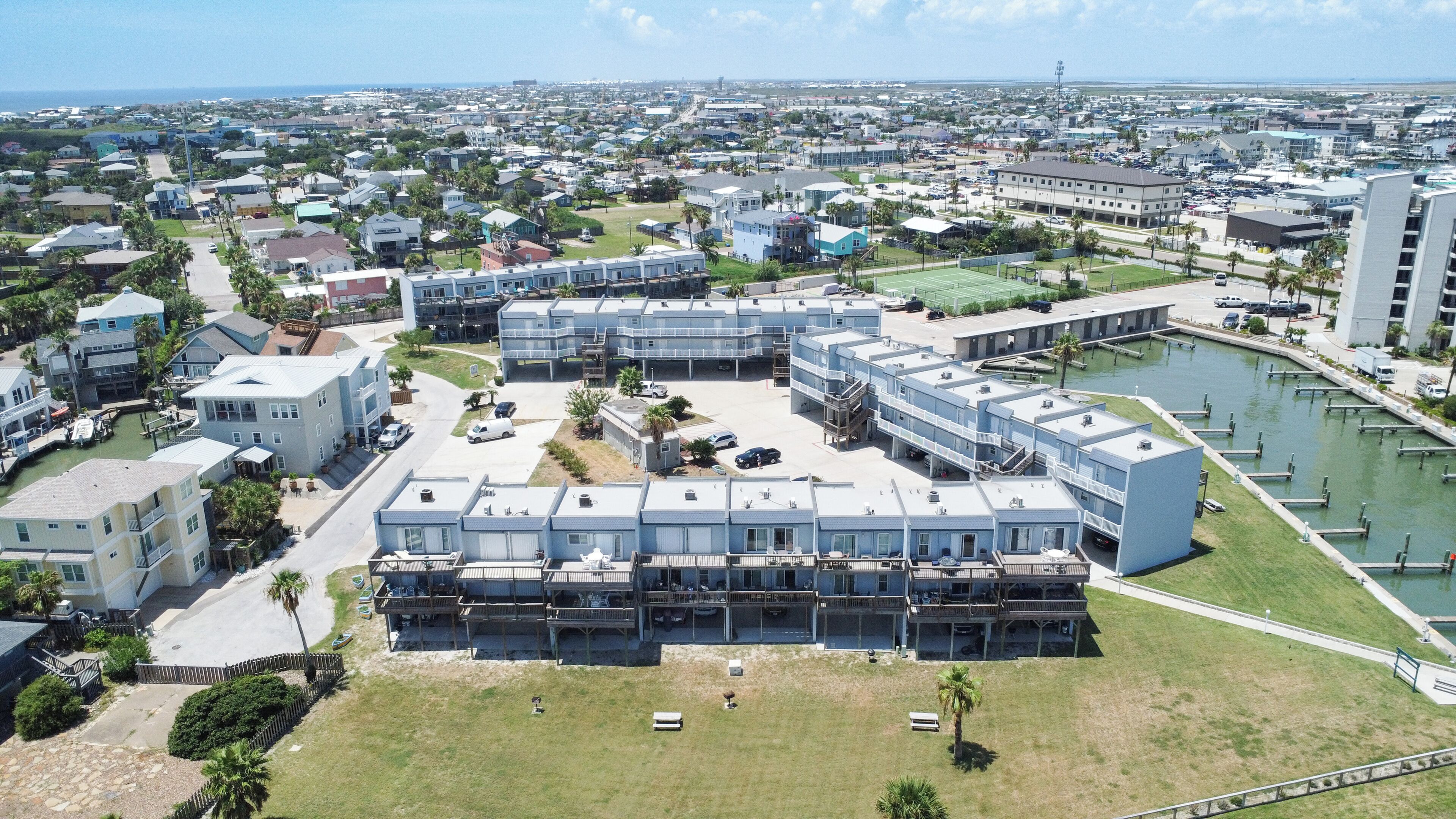 Een woongebied aan de kust met moderne appartementencomplexen, een jachthaven en een helder uitzicht op de oceaan.