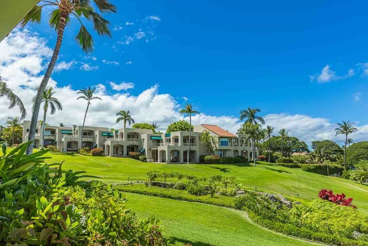 A resort with multiple buildings, lush green lawns, and palm trees.