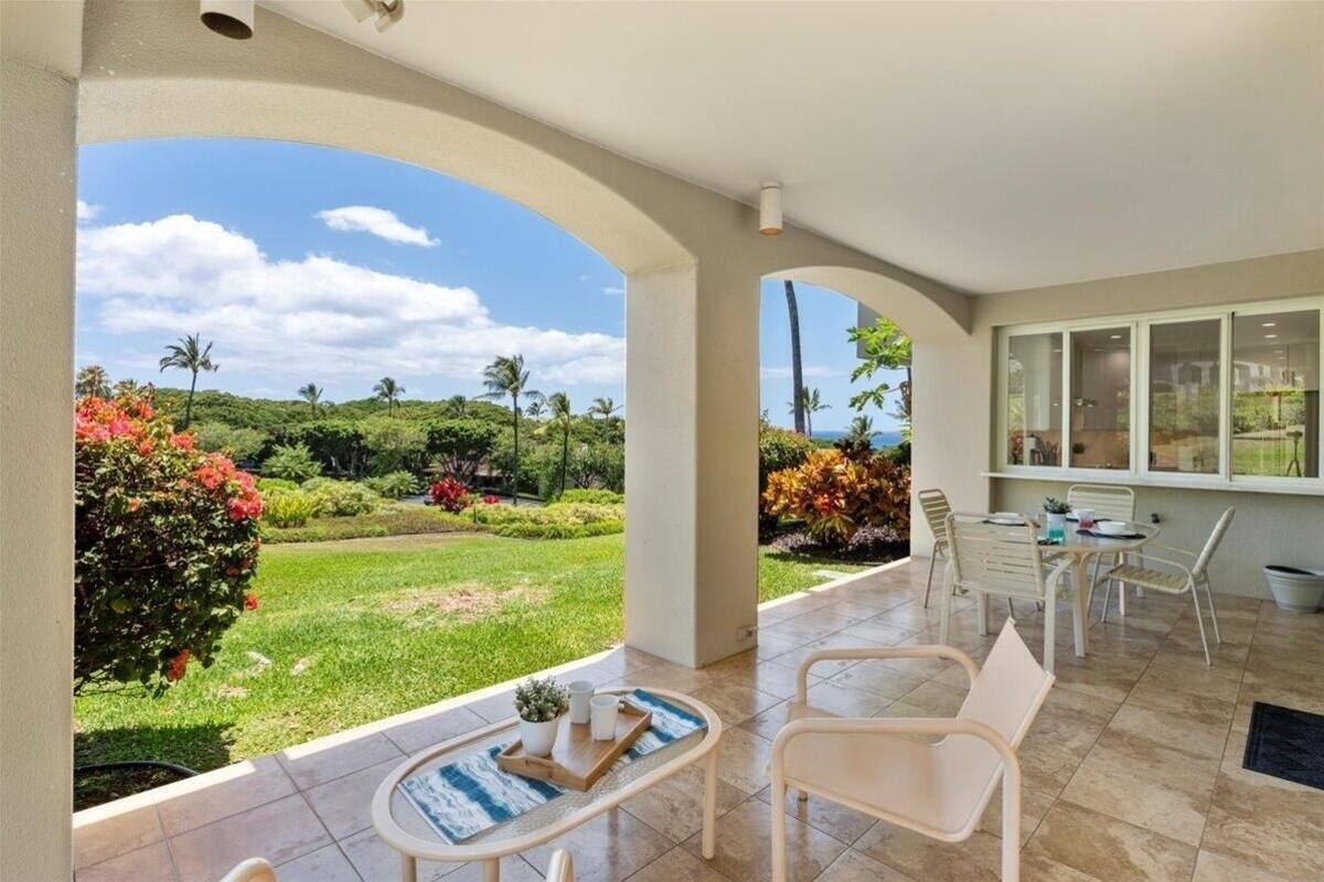 A spacious patio with a view of a lush garden and palm trees.