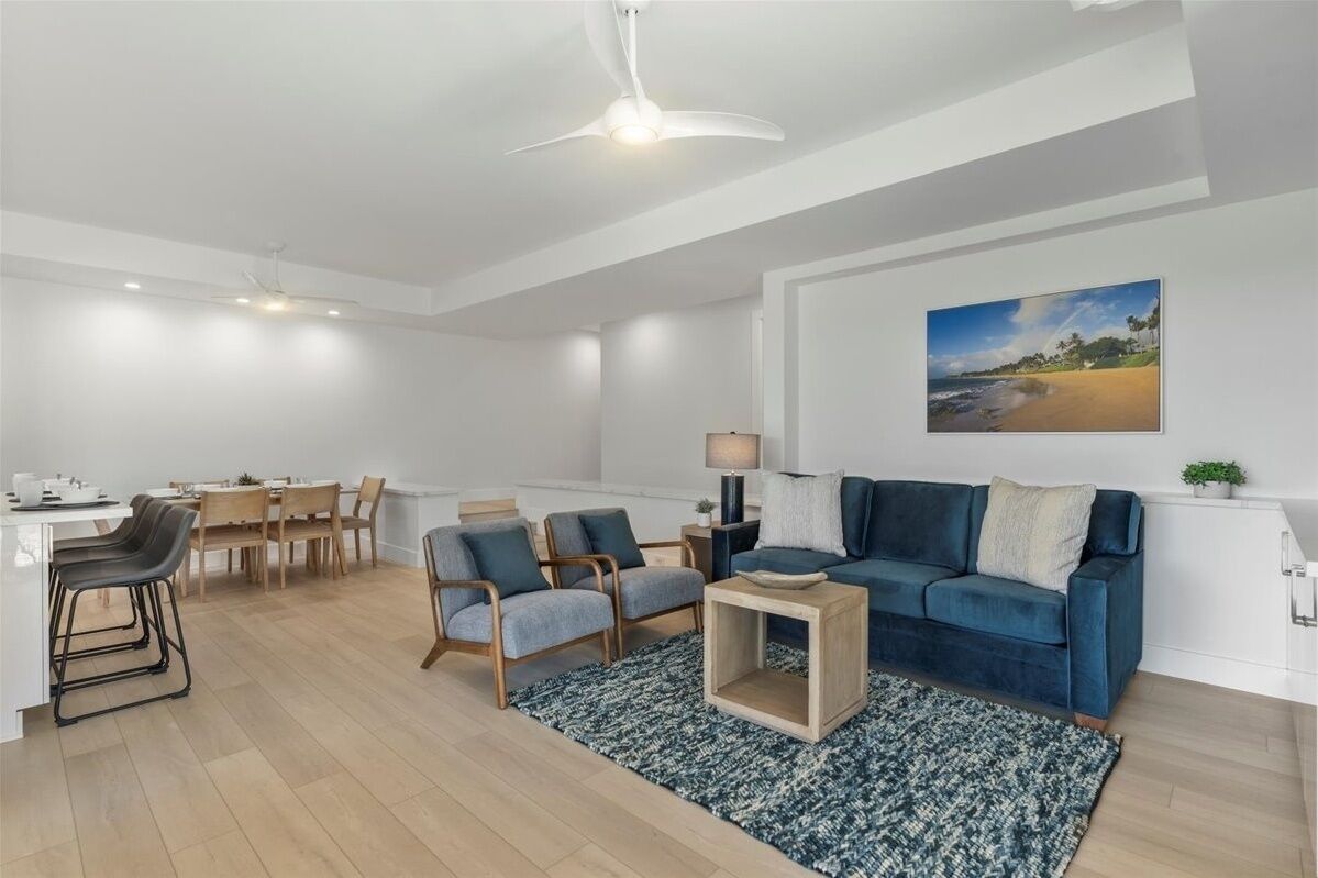 A modern living room with a blue sofa, wooden coffee table, and a dining area with a table and chairs.
