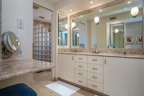 Un baño con un espejo grande, un lavabo y un mueble de tocador con cajones.