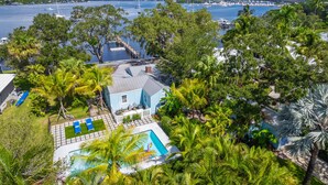 A coastal property with a swimming pool, a dock, and a view of the marina.