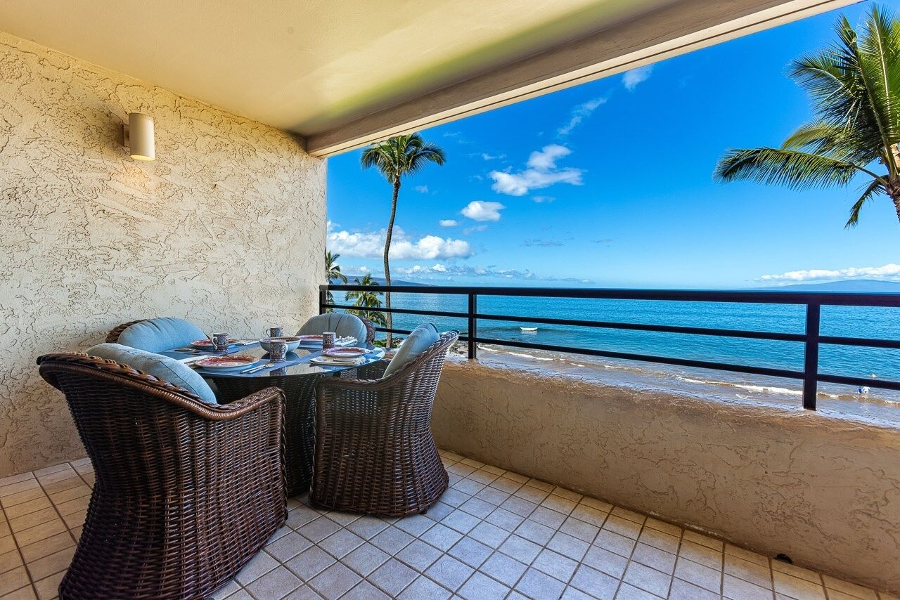 A balcony with wicker furniture and a view of the ocean.
