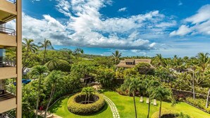A lush garden with palm trees, a circular lawn, and a building with a tiled roof. - Polo Beach Club Two Bedrooms - Sleeps 6 by Coldwell Banker Island Vacations (Kihei)