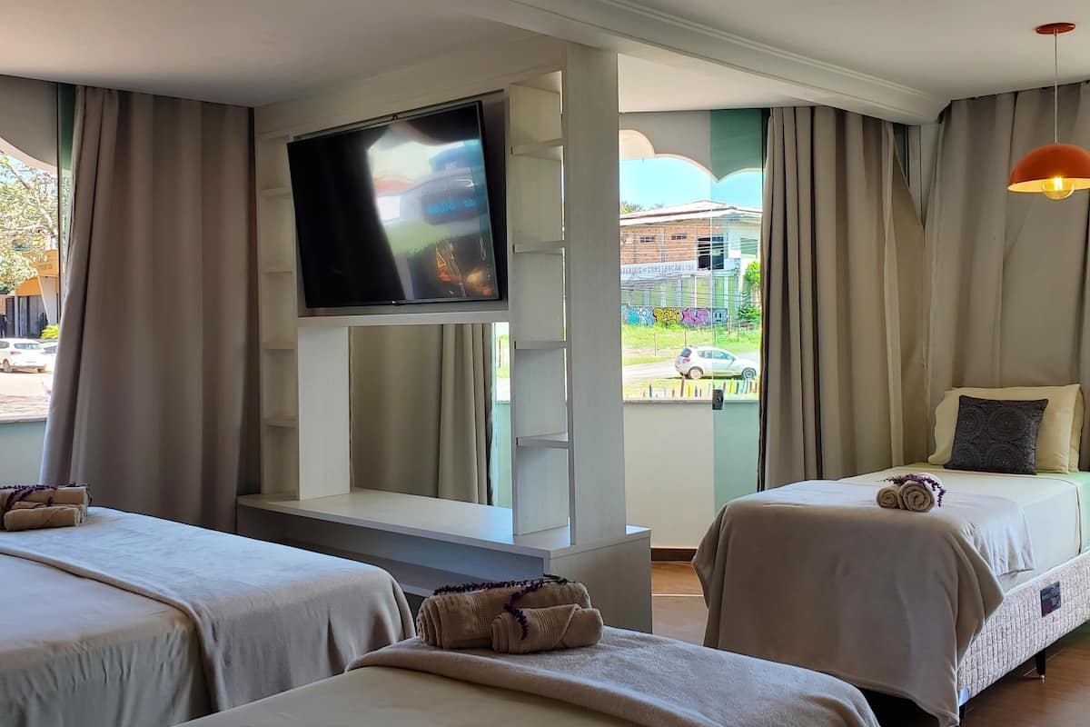 A hotel room with two beds, a TV, and a view of the outside.