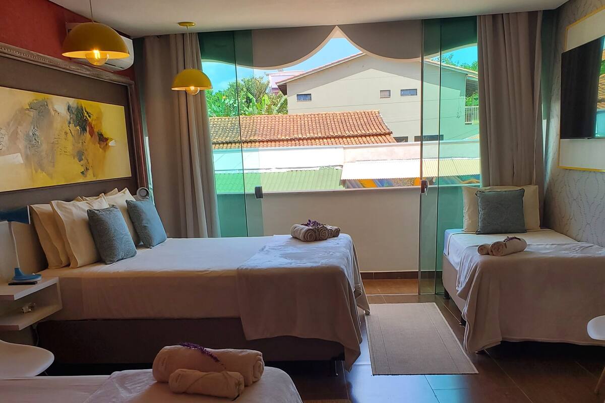 A hotel room with two beds, a large window, and a view of the outside.