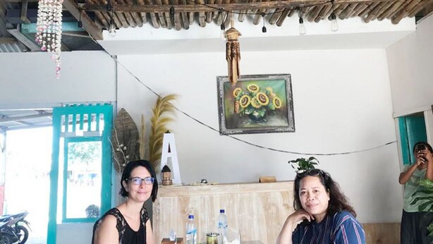 A rustic interior with a bamboo ceiling, a table with food, and a motorcycle outside. - A-Manta Homestay (Labuan Bajo)