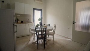 Una cucina compatta con mobili bianchi, un tavolo con sedie e una porta con finestra.