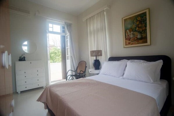 A bedroom with a large bed, a dresser, a chair, and a painting on the wall.