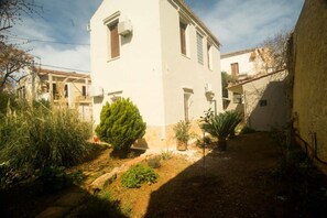 A white building with a small garden area, including a potted plant and a tree.