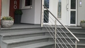 Ein Gebäudeeingang mit einer Treppe, einer Tür mit der Beschriftung "BURO" und der Nummer "7" an der Wand.