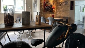 Ein zeitgenössischer Essbereich mit einer Steinwand, einem Motorrad und einem Tisch mit Weingläsern.