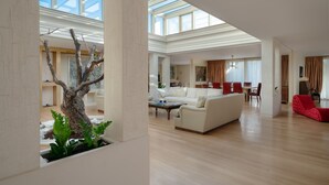 Un salón amplio con techo alto, una gran escultura de árbol y un sofá moderno.