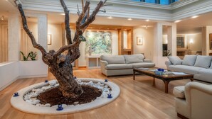 Amplia sala de estar con un gran árbol como elemento central, chimenea y techo alto con tragaluces.