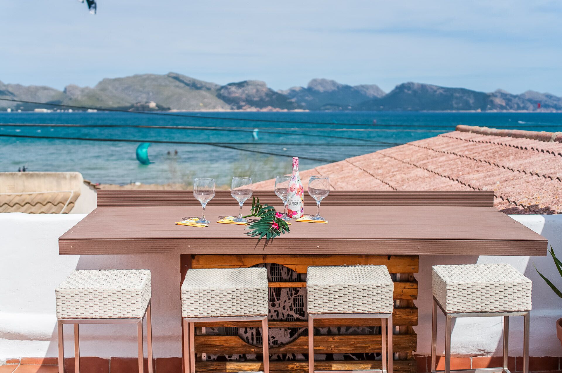 A table with four glasses and a bottle, set against a scenic ocean view.