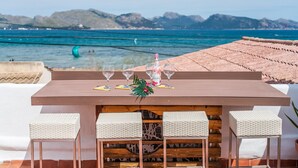 Une table avec quatre verres et une bouteille, placée devant un paysage marin pittoresque.