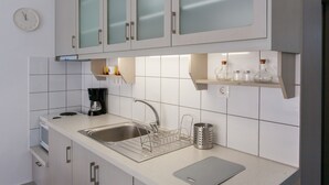 A modern kitchen with a stainless steel sink, a coffee maker, and a knife block. - Glaros Homes (Chania)
