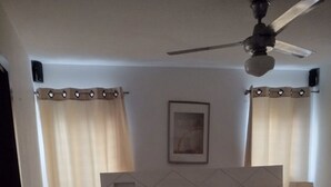 A bedroom with a bed, nightstands, a ceiling fan, and curtains. - GET AWAY Condo (Santiago De Los Caballeros)