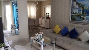 A modern living room with a sofa, coffee table, and a painting on the wall. - GET AWAY Condo (Santiago De Los Caballeros)