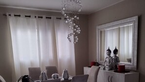 A dining area with a white table, four chairs, a decorative hanging light fixture, a cabinet with a mirror, and two Buddha statues. - GET AWAY Condo (Santiago De Los Caballeros)