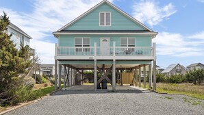 Une maison à deux étages avec un balcon, une véranda et une allée gravillonnée.