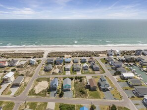 Luchtbeeld van een kustgebied met huizen, een jachthaven en een strand.