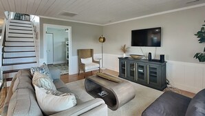 Un salon moderne avec un canapé gris, une table basse et un téléviseur fixé au mur.