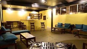 Un espace lounge accueillant, avec des meubles en bois, une cabine de DJ et un comptoir de bar.