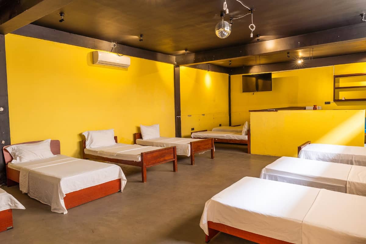 Habitación de hotel con cuatro camas individuales, un escritorio pequeño y un espejo en la pared.