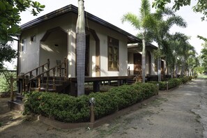A two-story building with a staircase leading to the entrance, surrounded by well-maintained hedges and palm trees. - Sunrise Cabanas (Arugam Bay)