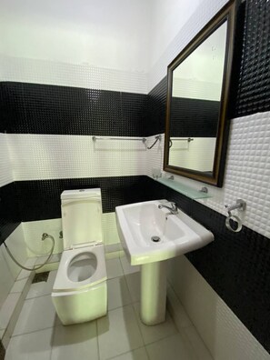 A bathroom with a toilet, sink, and mirror. - Sunrise Cabanas (Arugam Bay)