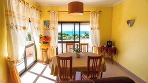 A dining area with a table and chairs, a hanging light fixture, and a view of the outdoors. - Casa Milu - (Nazaré)