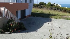 A modern two-story house with a flat roof, a balcony, and a paved driveway. - Casa Milu - (Nazaré)