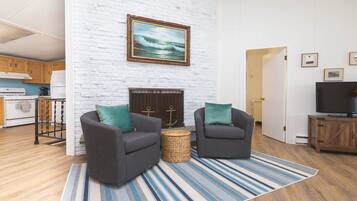 A living room with two grey sofas, a striped rug, a fireplace, and a television on a wooden cabinet.