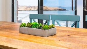 Una mesa de madera con una jardinera gris que contiene suculentas verdes.