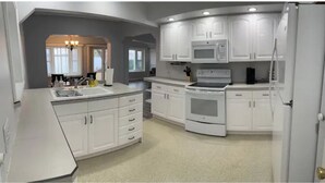 A modern kitchen with white cabinetry, a built-in microwave, and a stove.