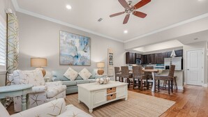 A spacious living room with a sofa, coffee table, and dining area. - Sunsets You'll Never Forget- Private Patio/Hot Tub/Heated Pool (Miramar Beach)