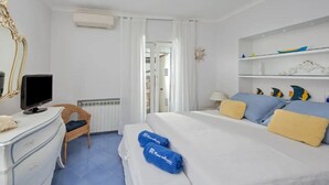 A hotel room with a bed, a TV, a dresser, and a chair. - Capri Charming mediterranean apartment (Marina Grande)