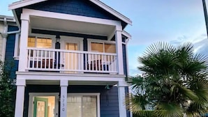 A two-story house with a balcony, a green door, and a number '5730' on the front.