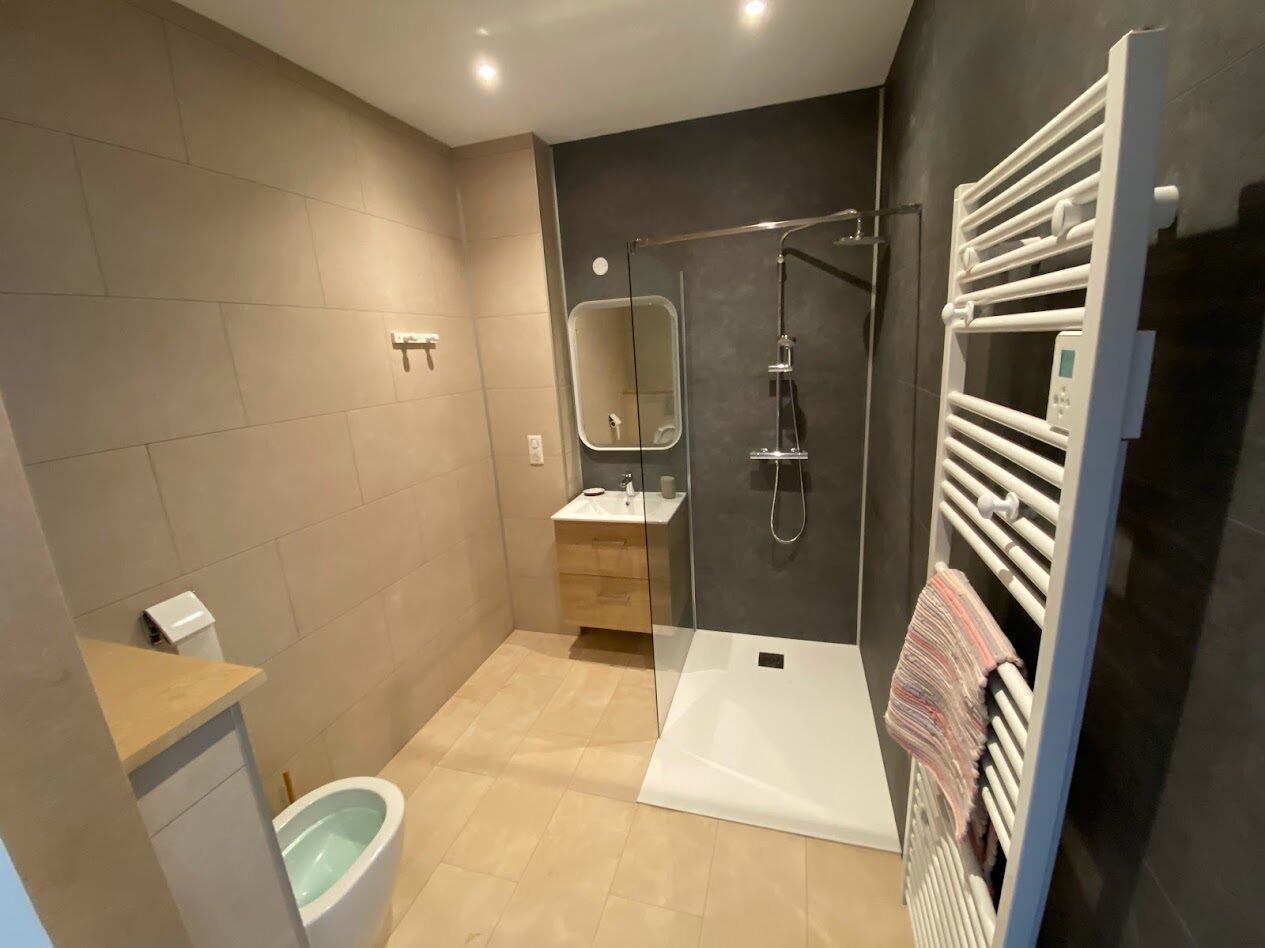 Een moderne badkamer met douche, toilet en wastafel.