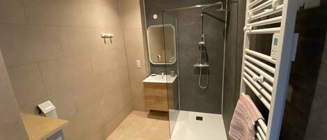 Een moderne badkamer met douche, toilet en wastafel.