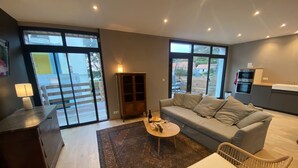Una sala moderna con un sofá, una mesa de centro y un comedor, con una cocina al fondo.