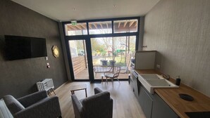 Una cocina moderna con un amplio ventanal, un televisor de pantalla plana y dos sillones grises.