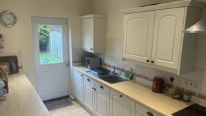 Une cuisine avec des meubles blancs, un four à micro-ondes, un évier et une cuisinière.