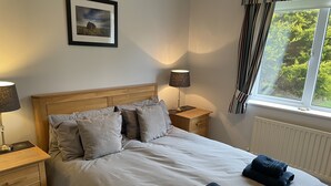 Un lit bien fait, avec des oreillers, une lampe de chevet et une table de nuit.