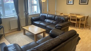 Un salon moderne avec un canapé en cuir, une table basse en bois et un coin repas comprenant une table et des chaises en bois.