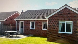 Une maison d’habitation avec une façade en briques, un toit en tuiles et une pelouse bien entretenue.