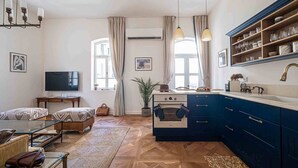 A compact living space with a kitchenette, a television, a sofa, and a dining table. - Authentic Restored Apt In The Old City (Tel Aviv-Yafo)