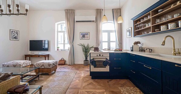 A compact living space with a kitchenette, a television, a sofa, and a dining table. - Authentic Restored Apt In The Old City (Tel Aviv-Yafo)