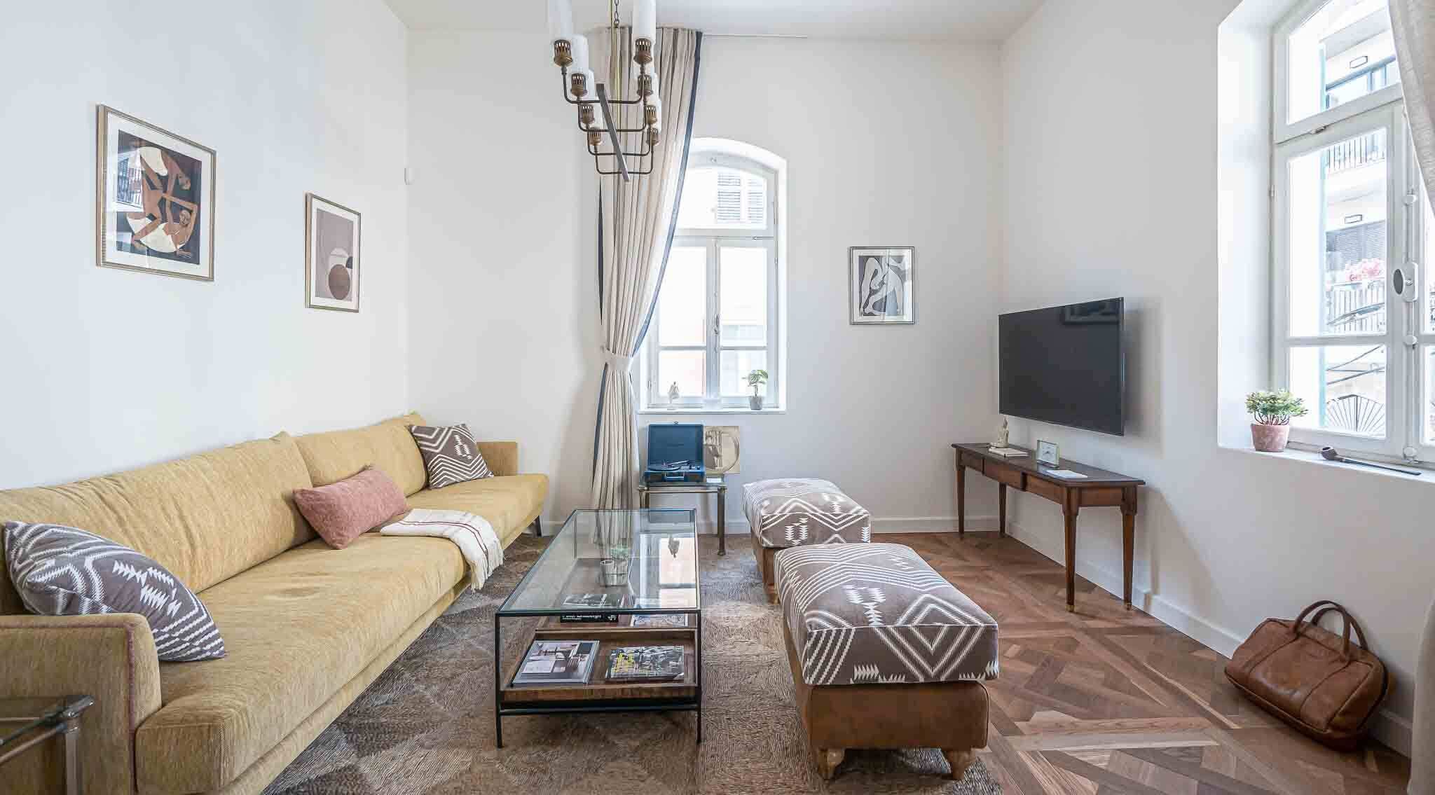 Un salon comprenant un canapé, un pouf, une table basse et un téléviseur à écran plat.